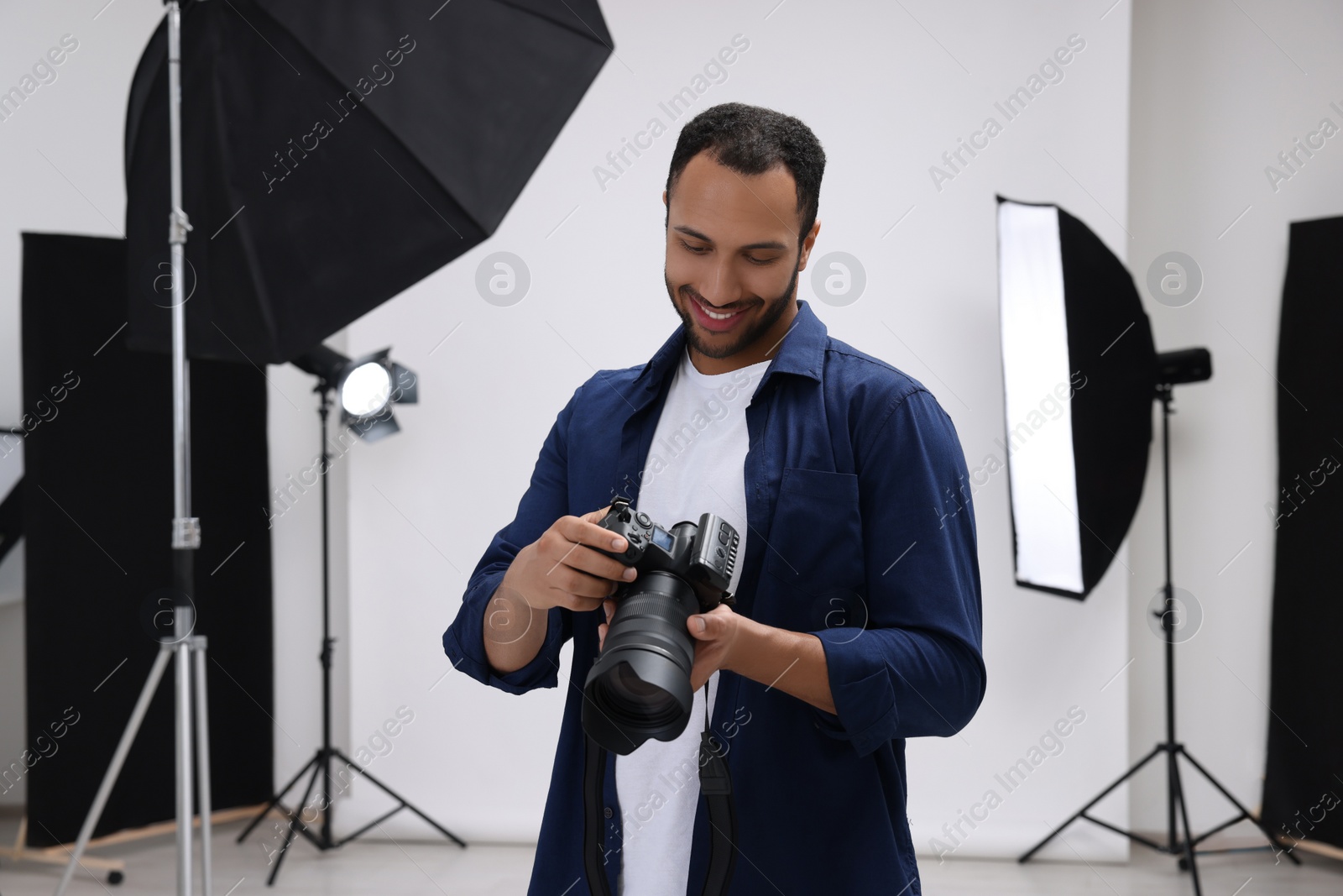 Photo of Young professional photographer with camera in modern photo studio, space for text