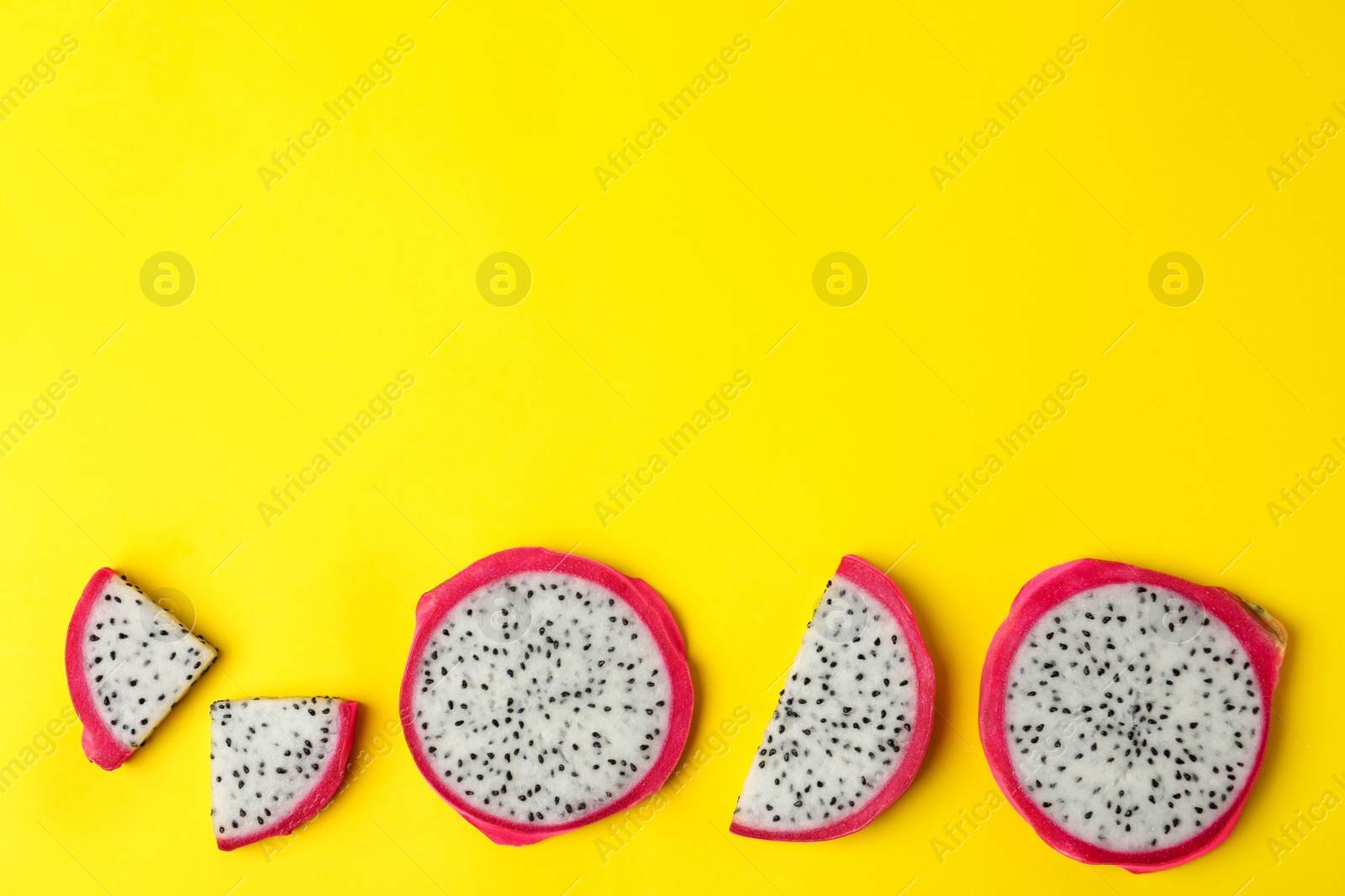 Photo of Delicious sliced dragon fruit (pitahaya) on yellow background, flat lay. Space for text