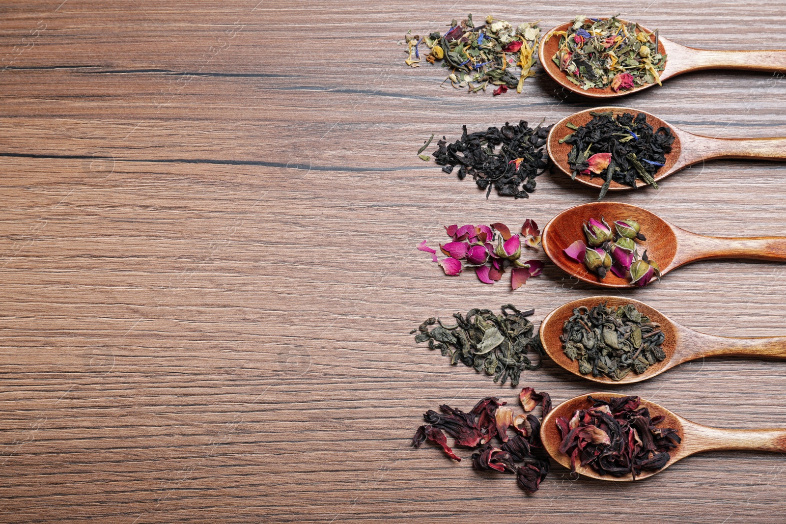 Photo of Flat lay composition with different teas and spoons on wooden table. Space for text