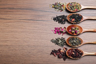 Photo of Flat lay composition with different teas and spoons on wooden table. Space for text