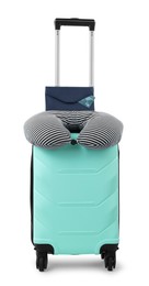 Photo of Soft travel pillow and purse on turquoise suitcase isolated on white