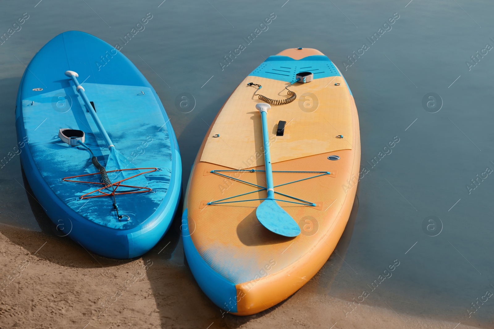 Photo of SUP boards with paddles on river shore