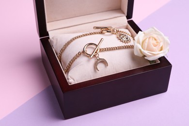 Photo of Beautiful jewelry and flower in box on color background, closeup