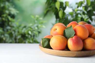 Many fresh ripe apricots on white table against blurred background. Space for text