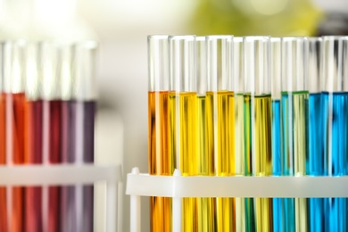 Photo of Test tubes with color liquids on blurred background, closeup view