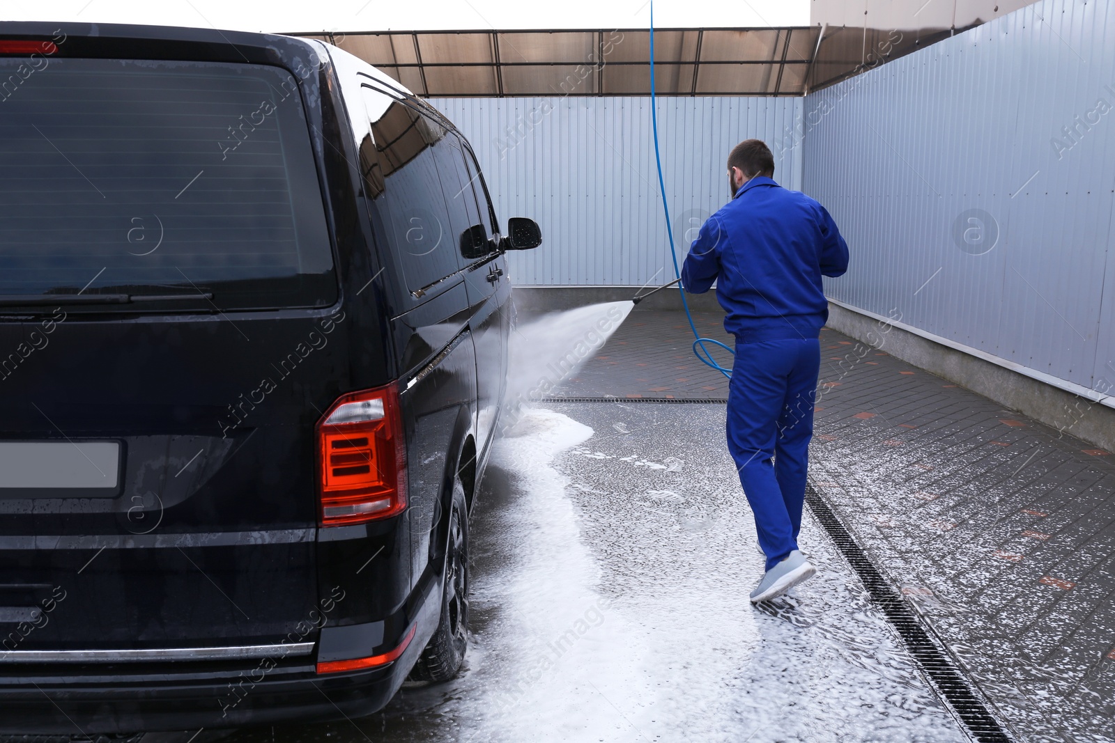 Photo of Worker cleaning automobile with high pressure water jet at car wash