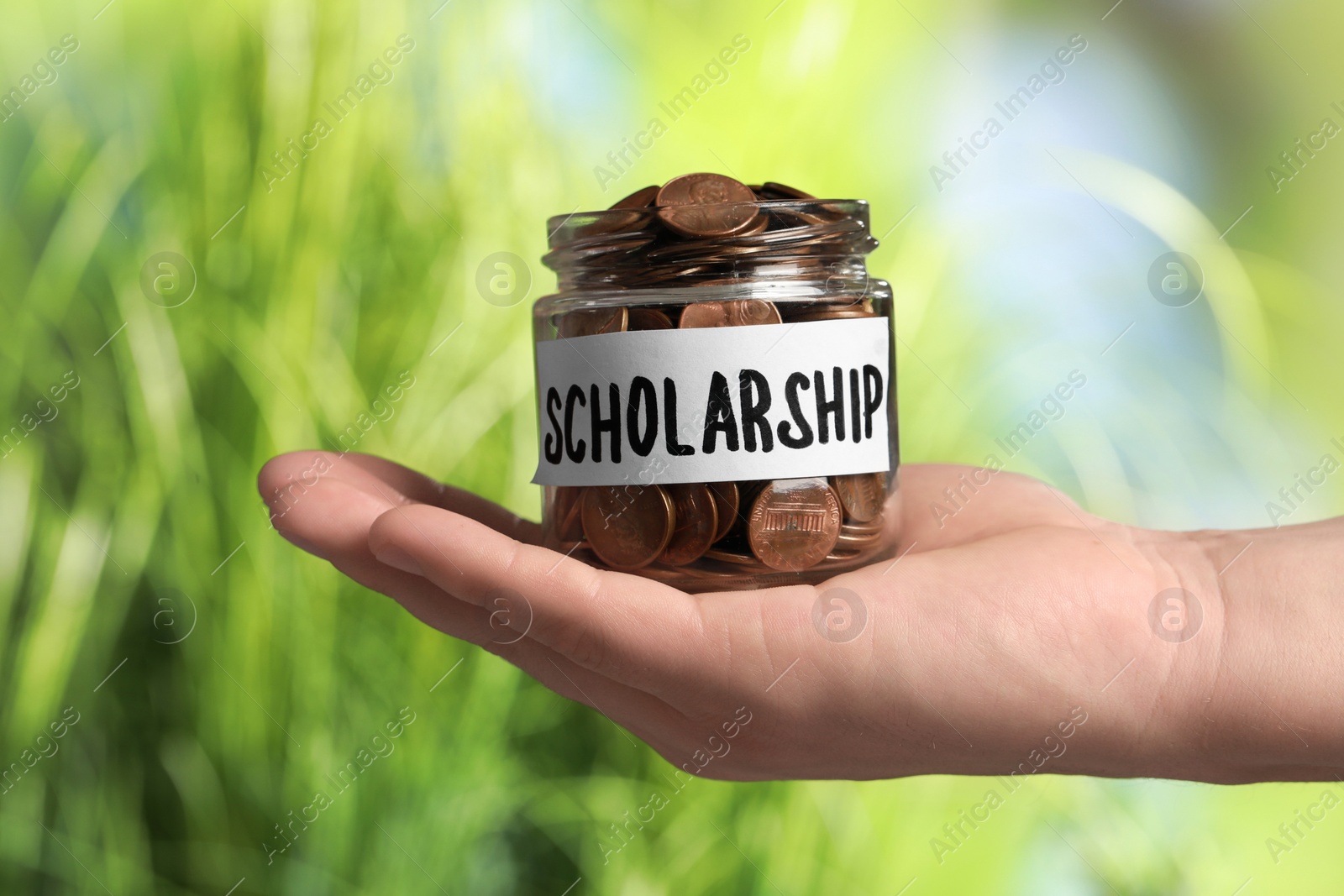 Photo of Man holding glass jar with coins against blurred background, closeup. Scholarship concept