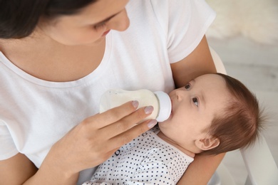 Photo of Woman feeding her baby from bottle at home, closeup
