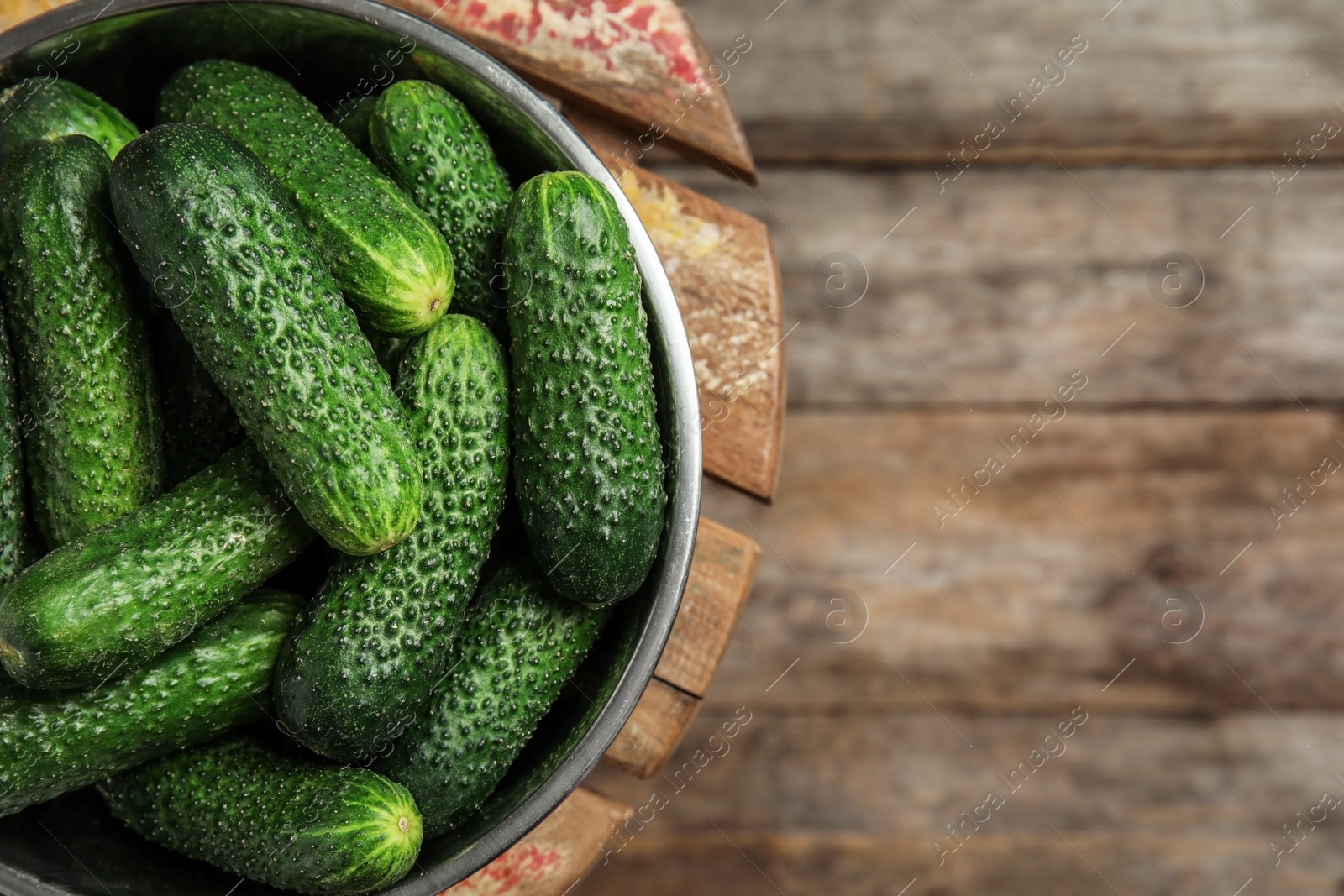 Photo of Bowl with ripe fresh cucumbers on table, top view