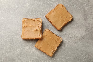 Photo of Tasty peanut butter sandwiches on gray table, flat lay