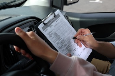 Photo of Driving school. Student passing driving test with examiner in car, closeup