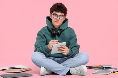 Photo of Portrait of student with notebook and stationery sitting on pink background