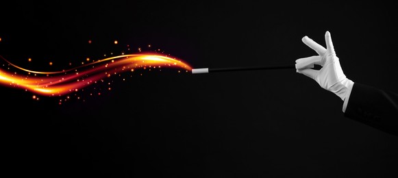 Image of Magician showing trick with wand black background, closeup. Banner design