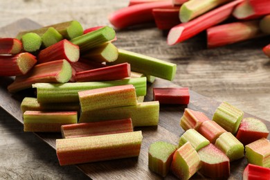 Many cut rhubarb stalks on wooden table, closeup