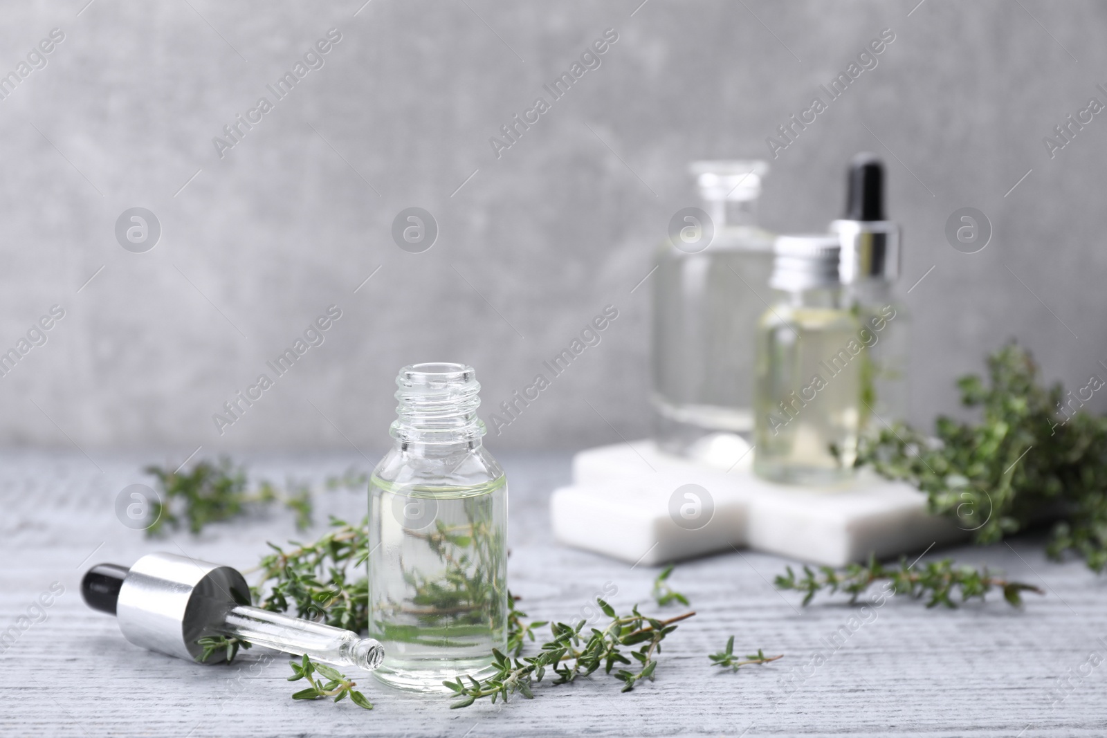 Photo of Thyme essential oil on light blue wooden table, space for text