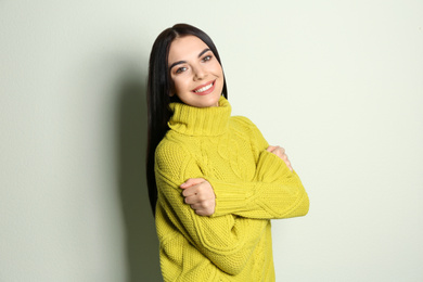 Photo of Young woman wearing warm sweater on light background. Winter season