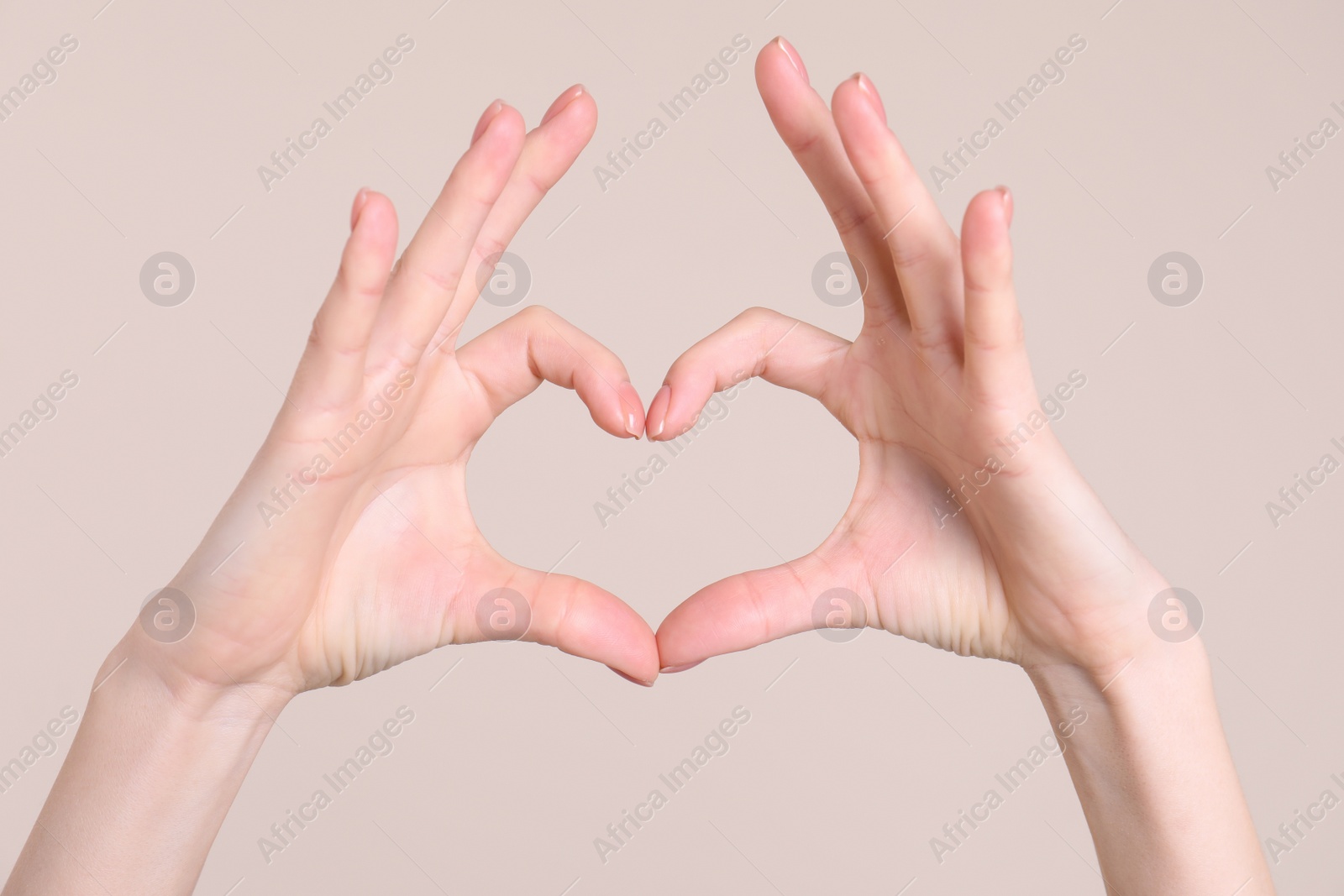 Photo of Young woman making heart with her hands on color background, closeup