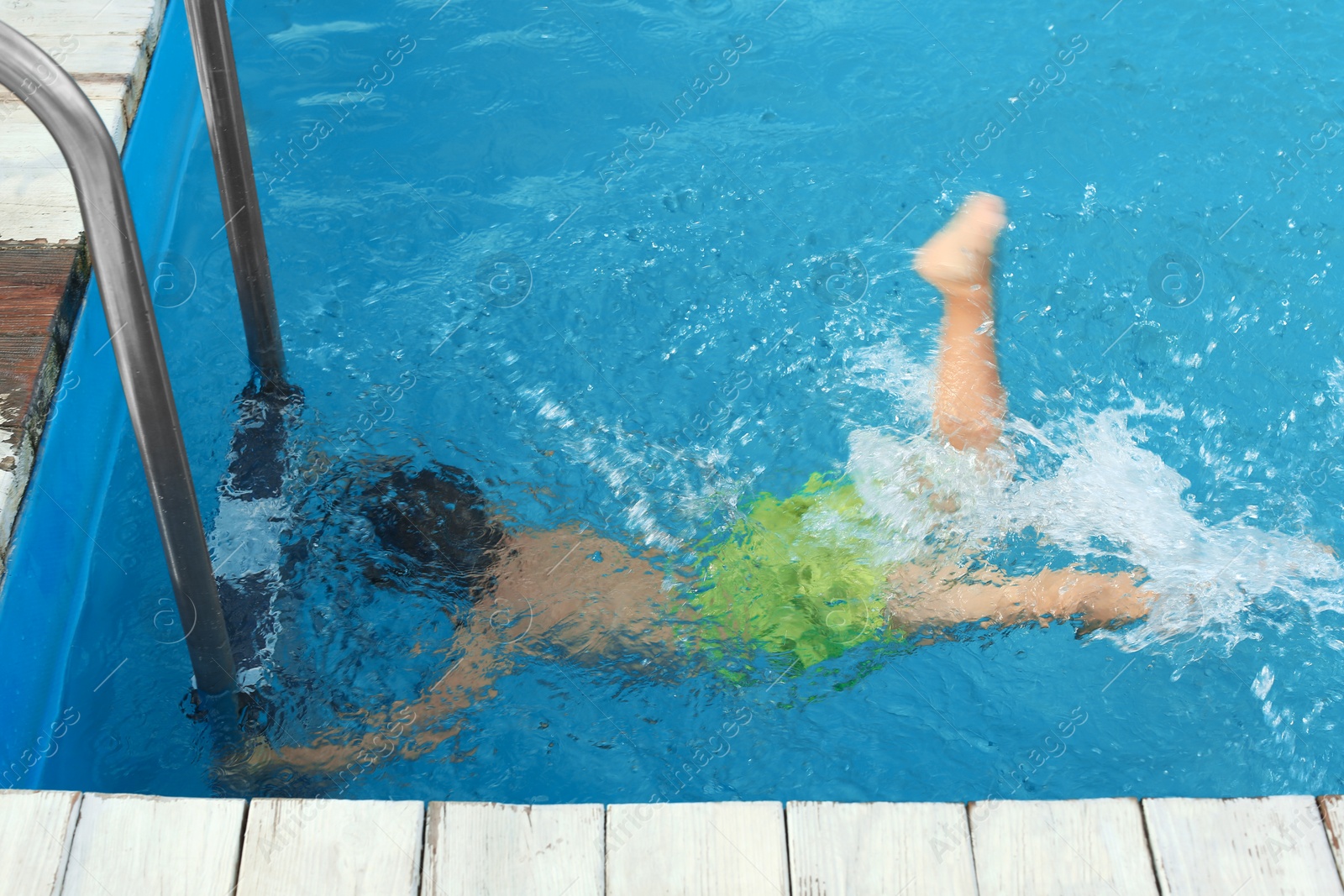 Photo of Little child under water in outdoor swimming pool. Dangerous situation