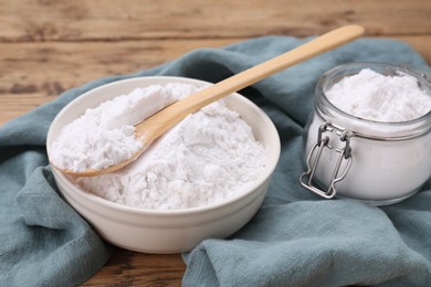 Photo of Bowl, spoon and glass jar of natural starch on wooden table, closeup