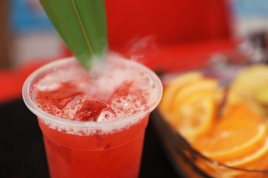 Photo of Delicious refreshing drink in plastic cup on bar counter, closeup