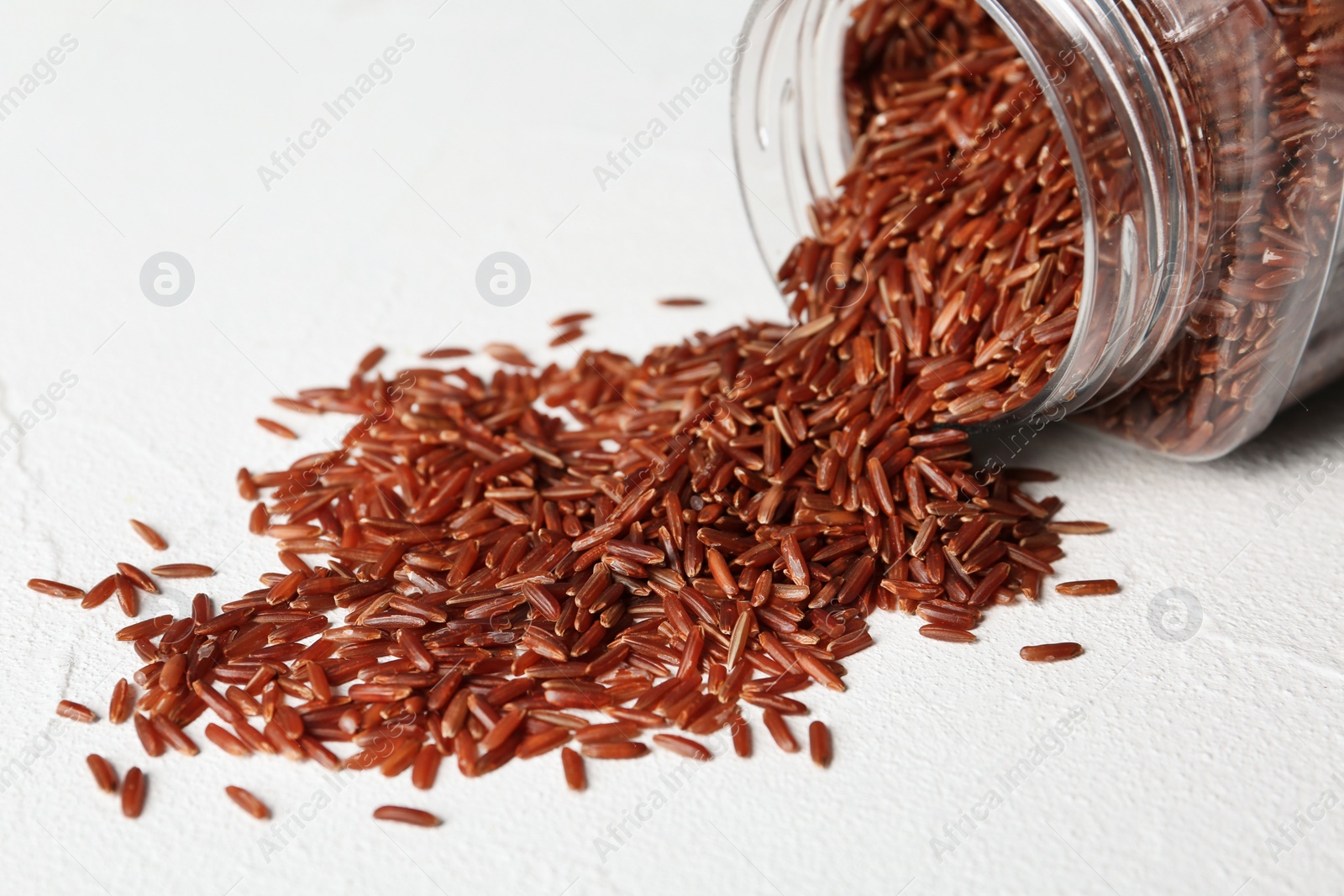 Photo of Pile of brown rice and jar on table, closeup