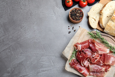 Photo of Tasty prosciutto on grey table, flat lay. Space for text