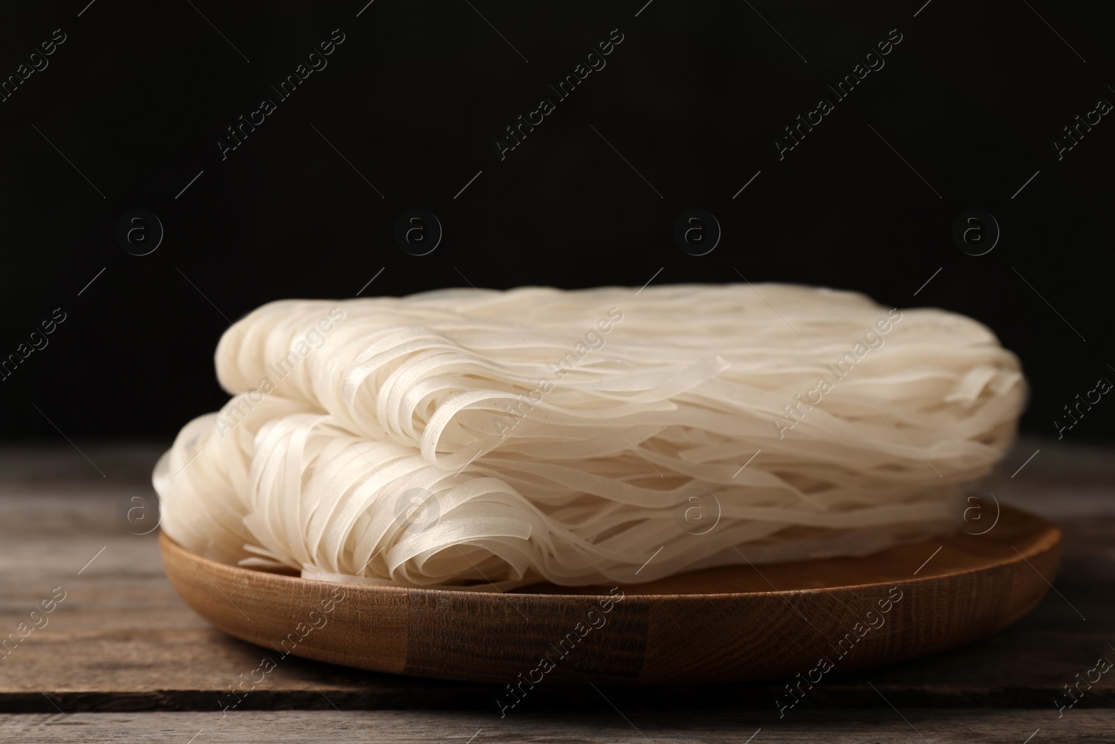 Photo of Plate with raw rice noodles on wooden table