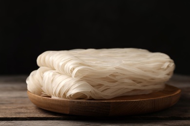 Plate with raw rice noodles on wooden table