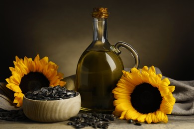 Sunflower cooking oil, seeds and yellow flowers on light grey table