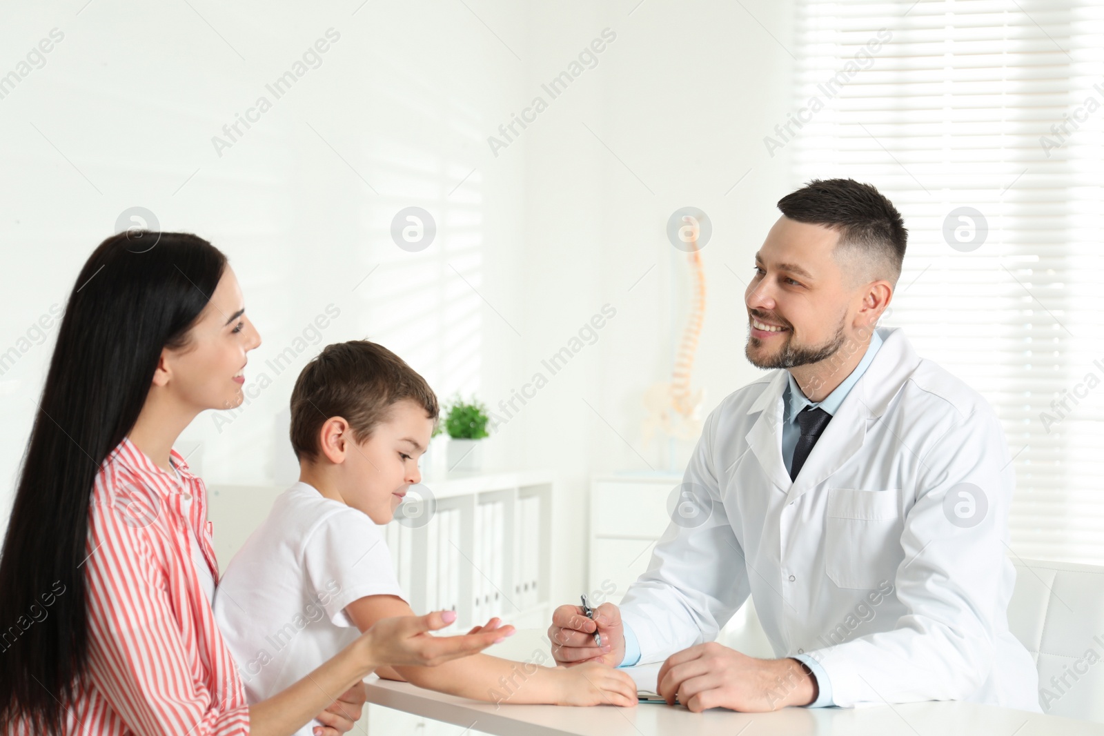 Photo of Little boy with mother visiting orthopedist at clinic