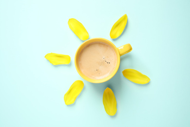 Photo of Cup of morning coffee and tulip petals on light blue background, flat lay