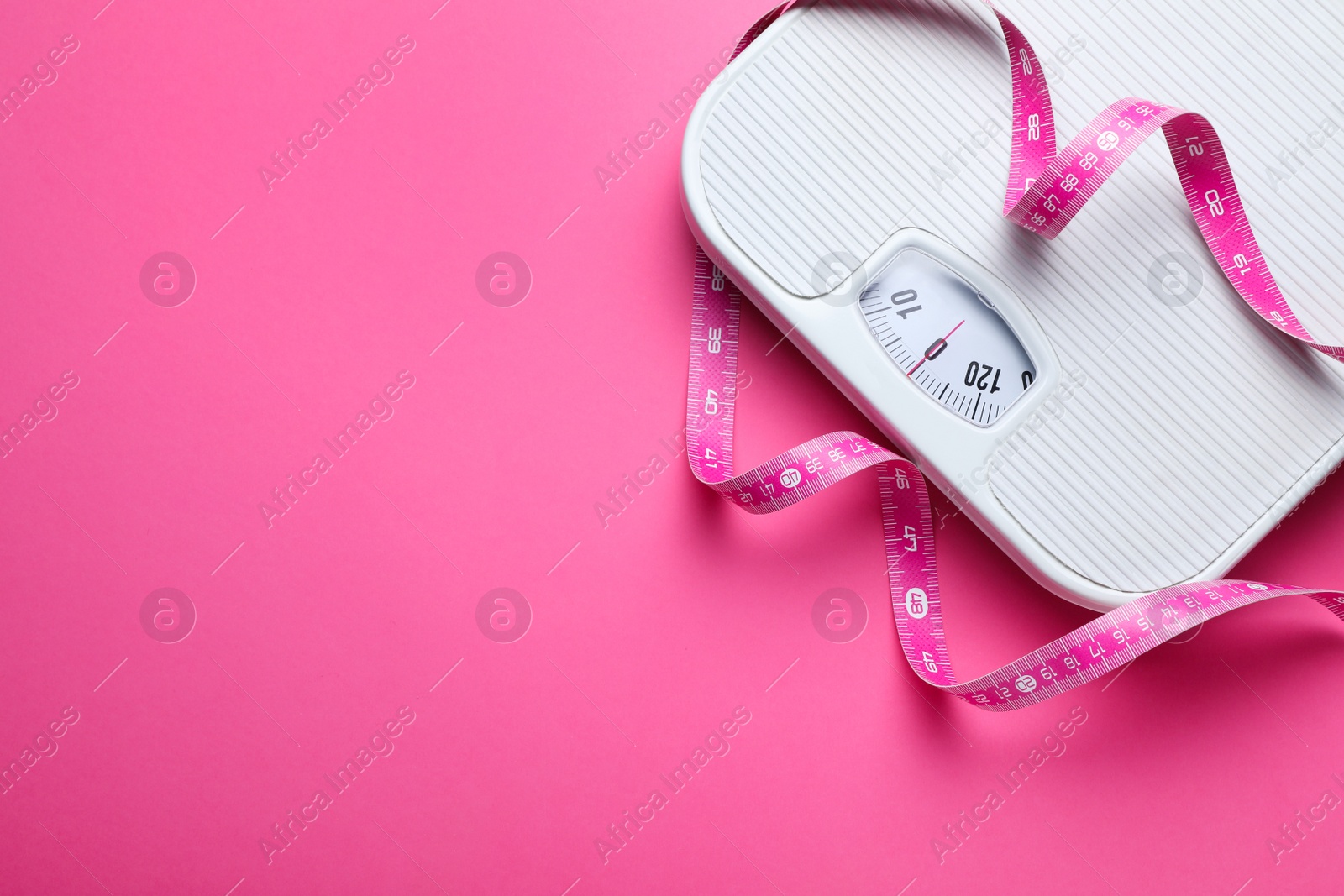 Photo of Scales and measuring tape on pink background, flat lay. Space for text