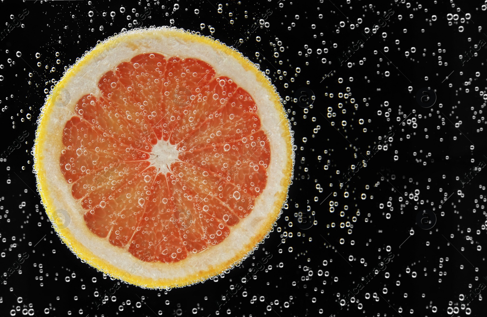 Photo of Slice of grapefruit in sparkling water on black background. Citrus soda