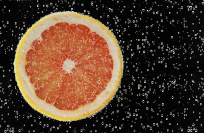 Slice of grapefruit in sparkling water on black background. Citrus soda