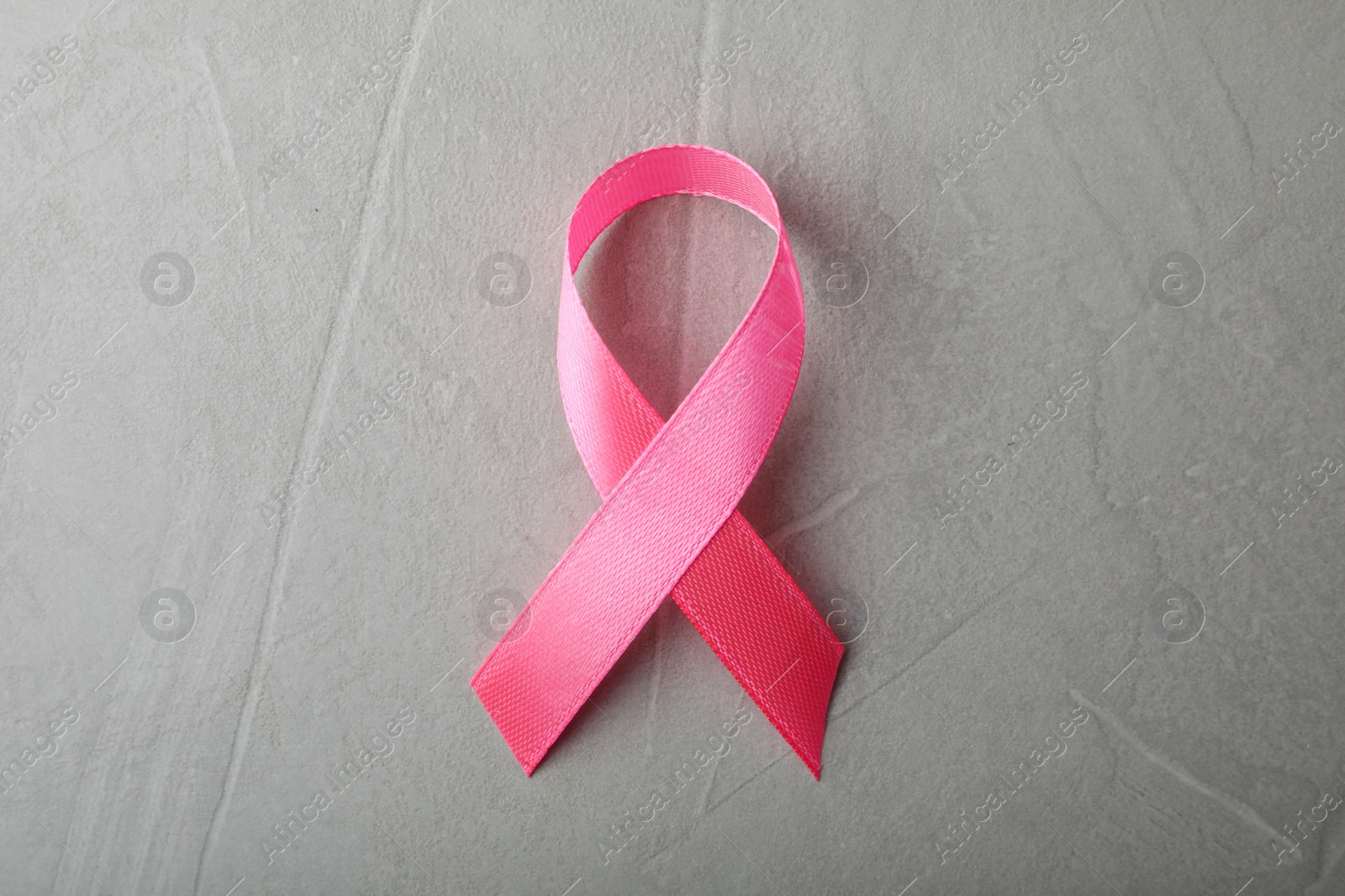 Photo of Pink ribbon on grey background, top view. Breast cancer awareness concept