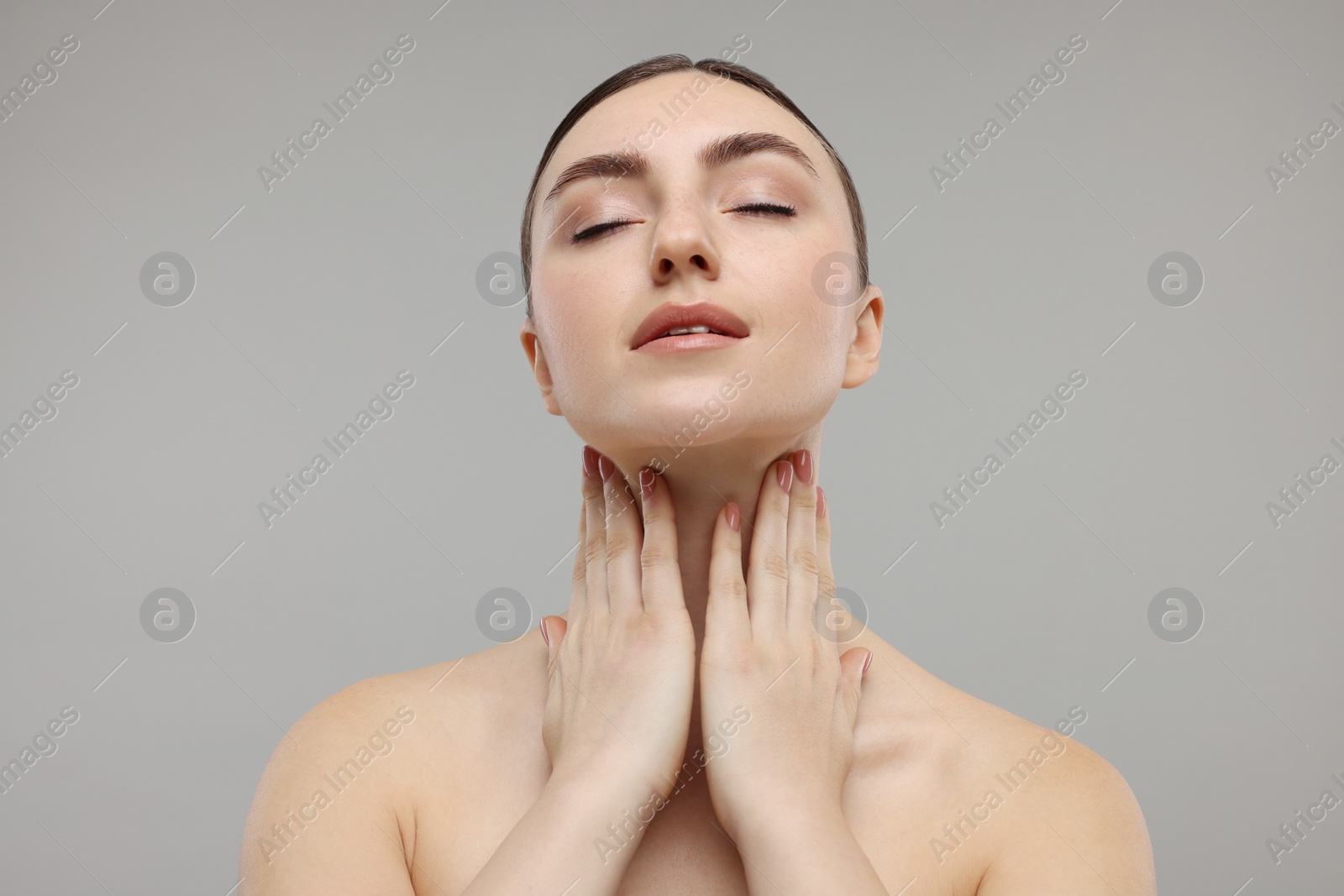 Photo of Beautiful woman touching her neck on grey background