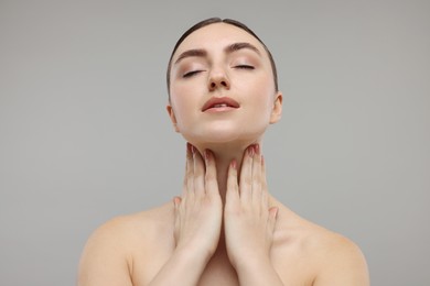 Photo of Beautiful woman touching her neck on grey background