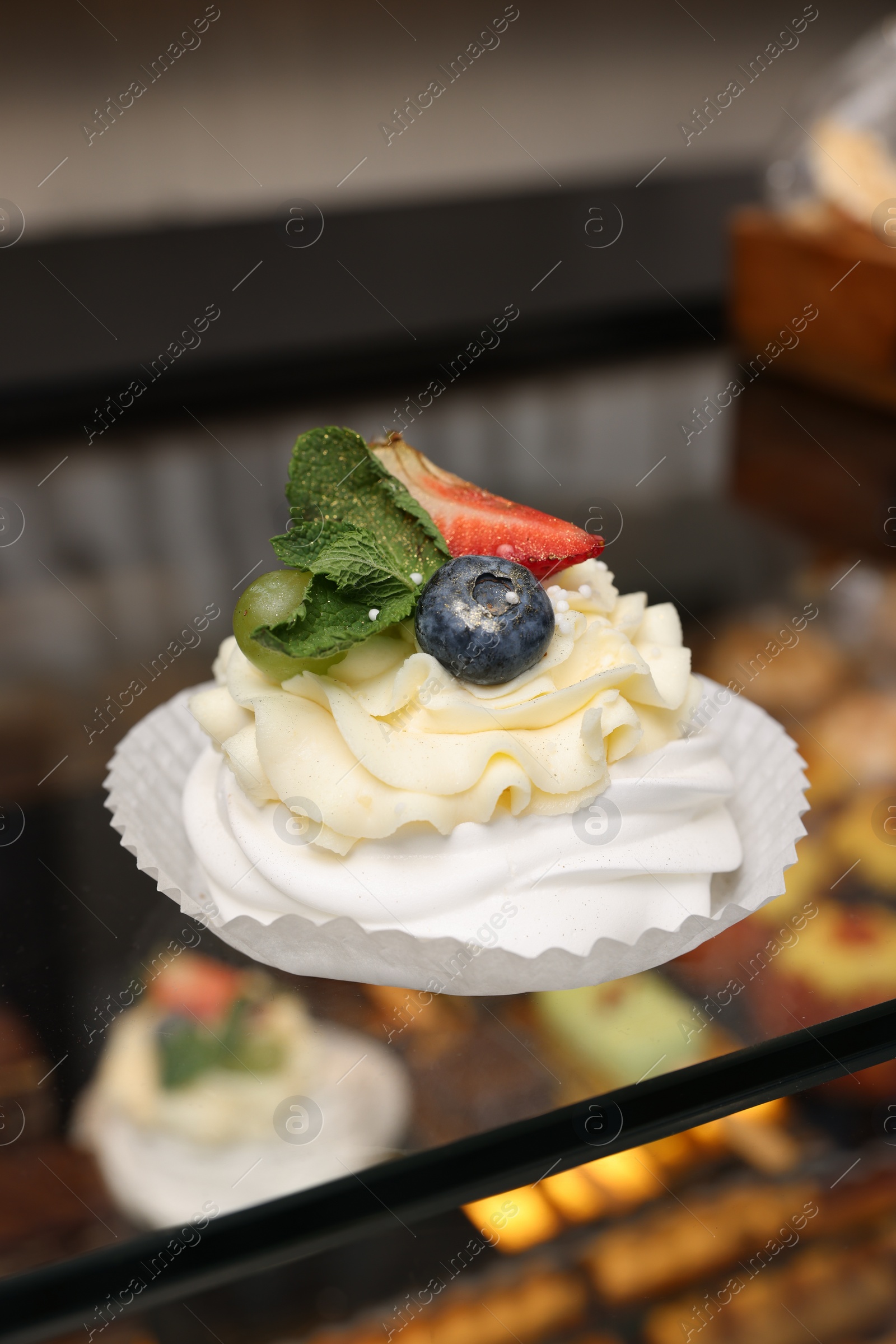 Photo of Delicious meringue dessert on counter in bakery shop, closeup. Space for text