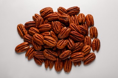 Photo of Pile of delicious fresh pecan nuts on white background, top view