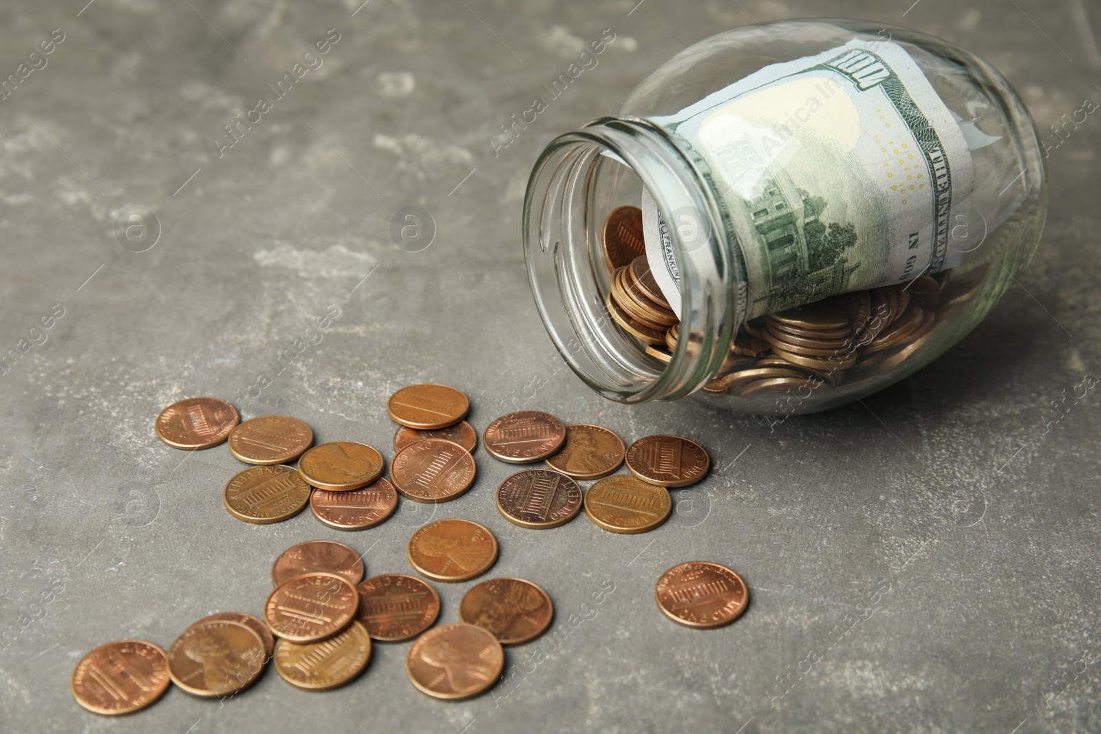 Photo of Overturned glass jar with money on grey stone table