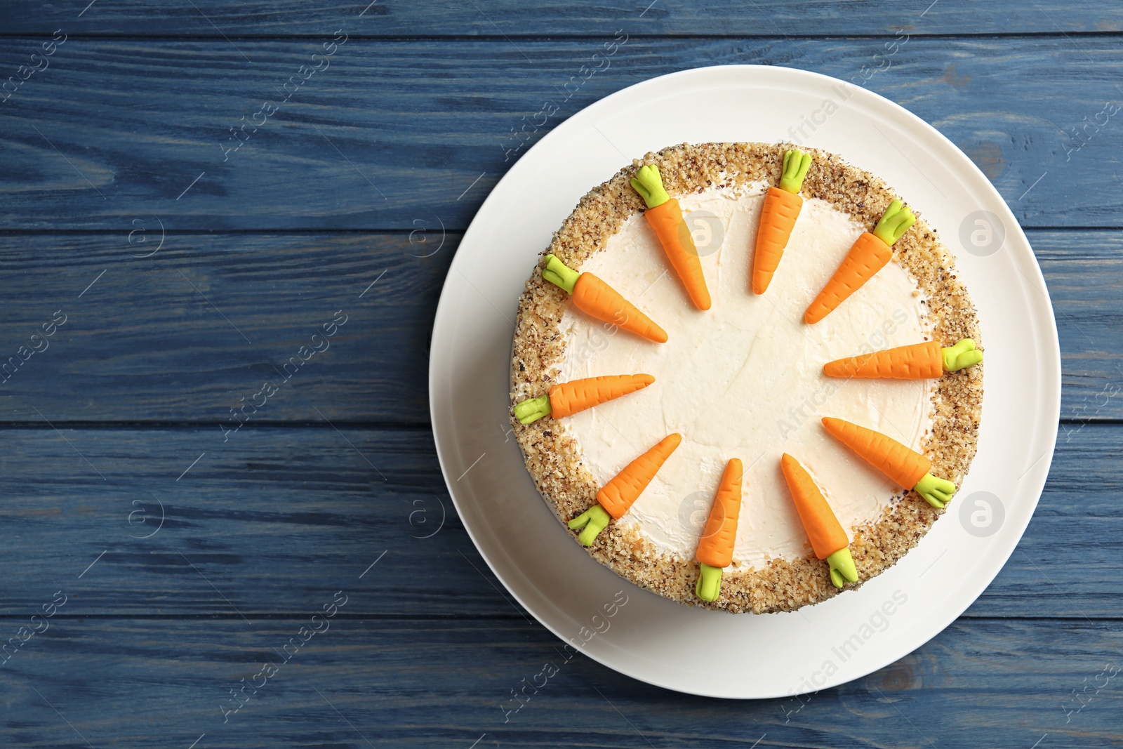 Photo of Dish with delicious carrot cake on blue wooden background, top view. Space for text