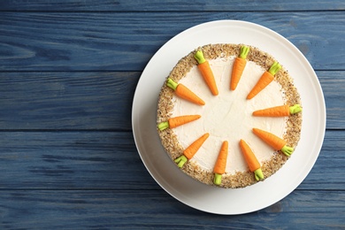 Dish with delicious carrot cake on blue wooden background, top view. Space for text