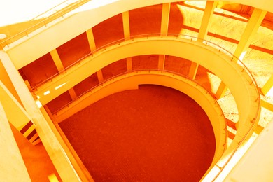 Image of Open car parking garage with ramp on sunny day, above view. Toned in orange color