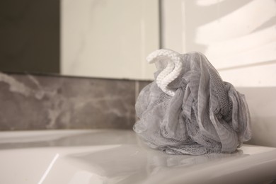 Photo of Grey shower puff on washbasin in bathroom, closeup. Space for text