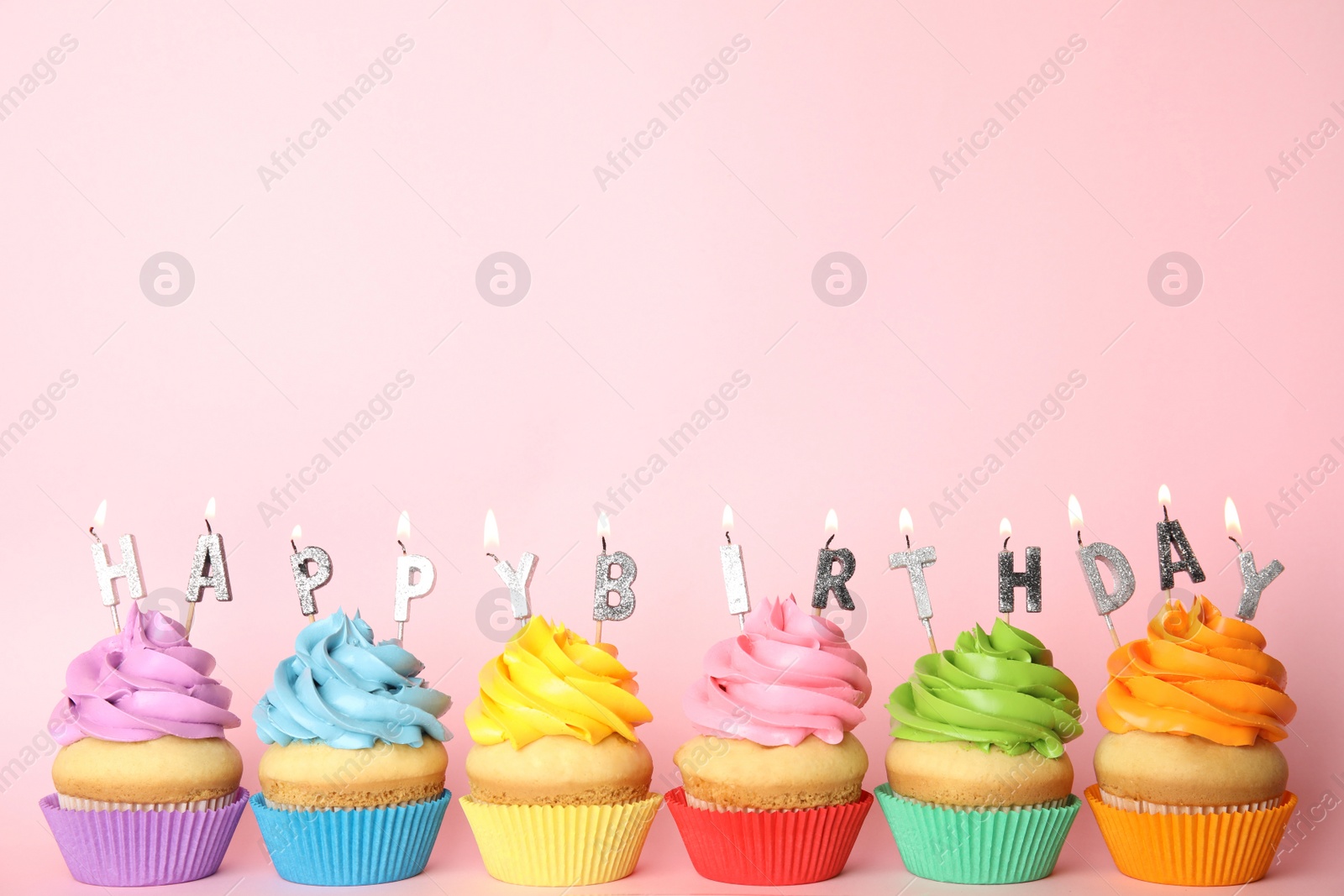 Photo of Birthday cupcakes with burning candles on pink background. Space for text