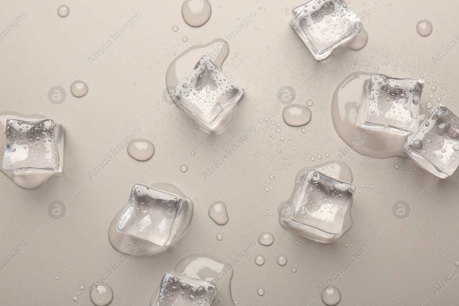 Photo of Melting ice cubes and water drops on light grey background, flat lay