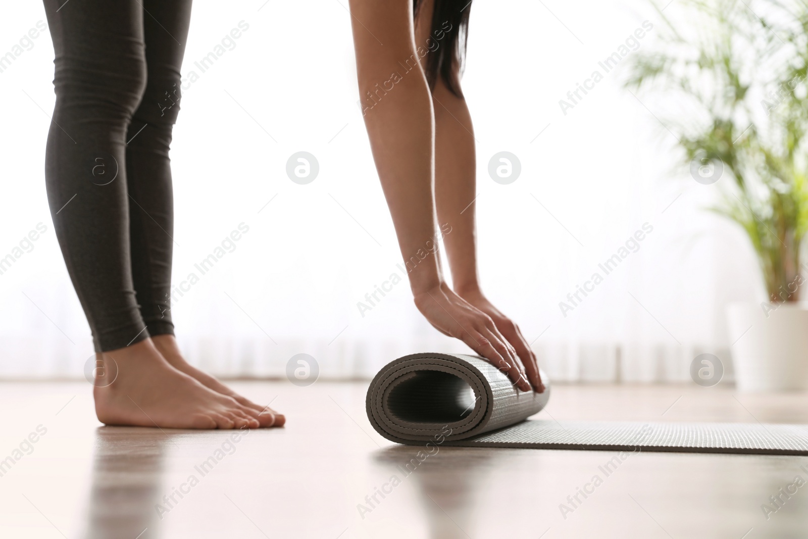 Photo of Woman rolling yoga mat in studio, closeup