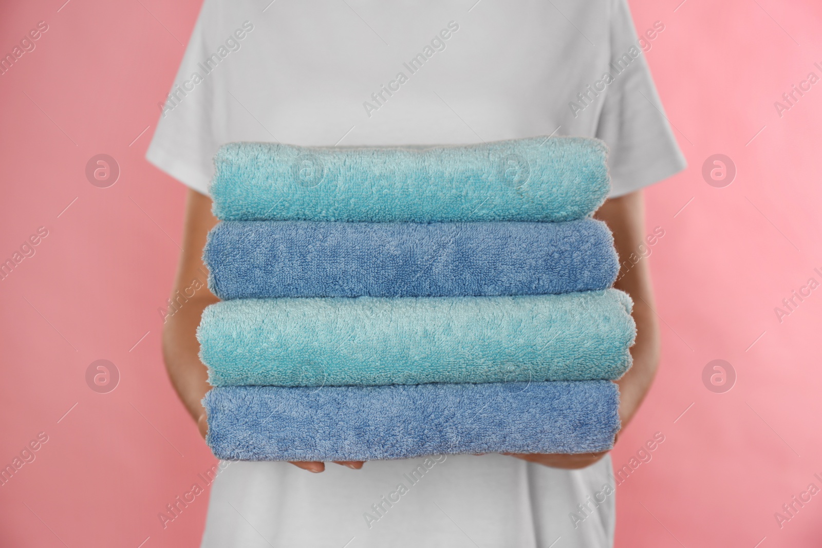 Photo of Woman holding fresh towels on pink background, closeup