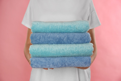 Photo of Woman holding fresh towels on pink background, closeup