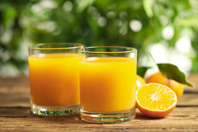 Glasses of fresh tangerine juice and fruits on wooden table